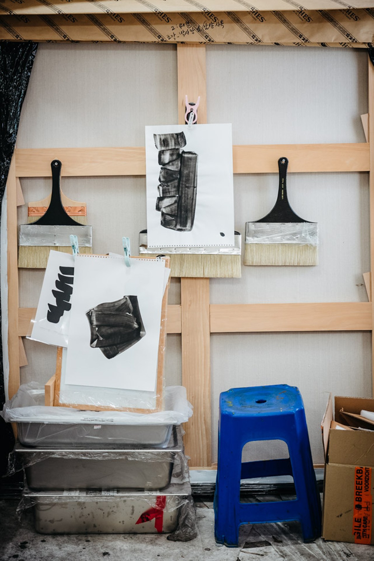 Artist Lee Bae's studio workspace with charcoal drawings pinned to wooden frames.