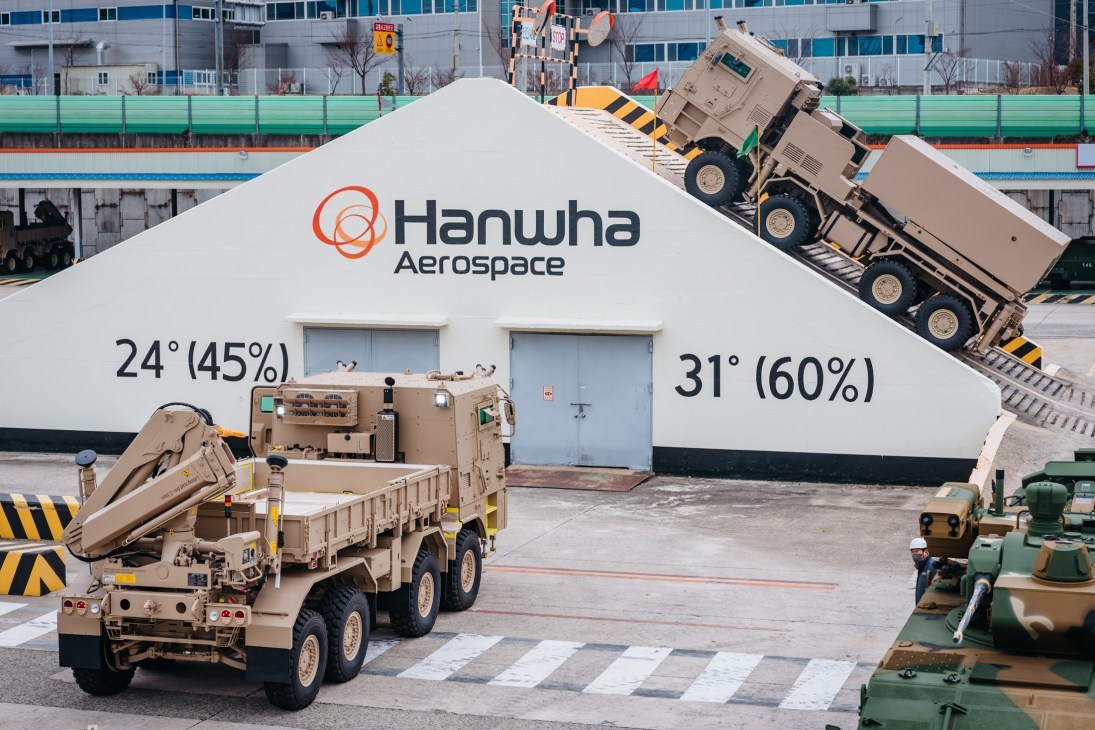 Military truck performing steep incline test at Hanwha Aerospace facility with angle measurements displayed.
