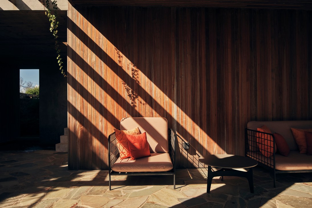 Chair with orange cushion and red pillow in sunlit covered area at Posada Ayana.