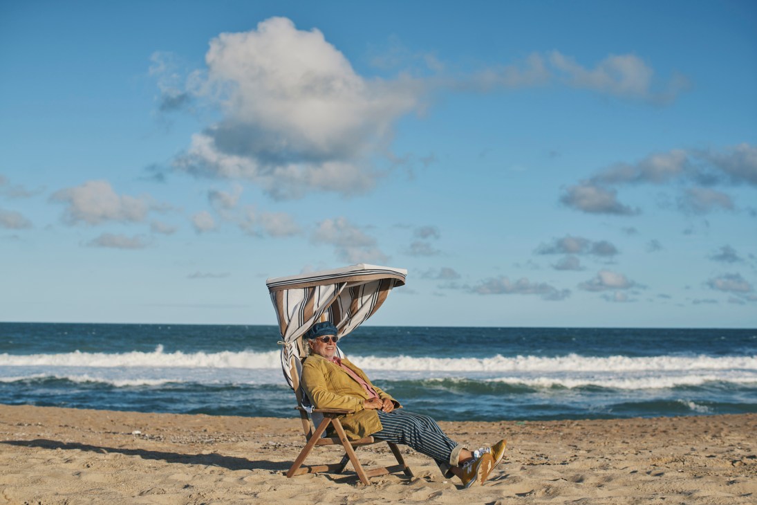 Chef Francis Mallmann relaxing in a beach chair with a canopy on the sand at José Ignacio.