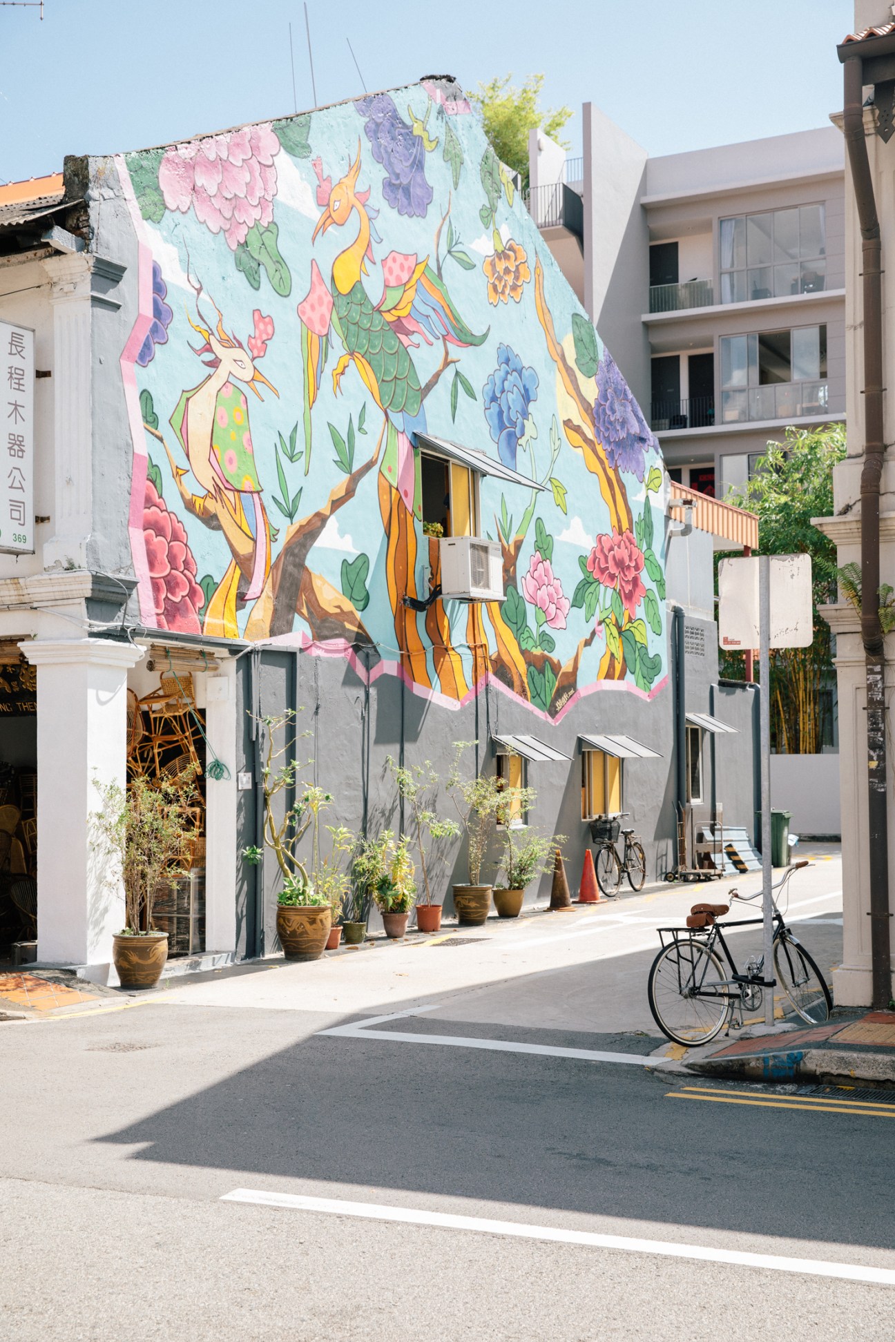 Colorful floral mural painted on building wall in Singapore street with bicycles parked below