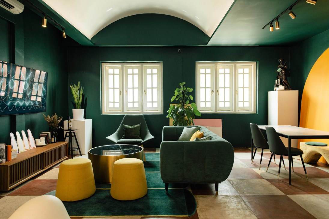 Modern green lounge interior with curved sofa, yellow ottomans, and arched ceiling