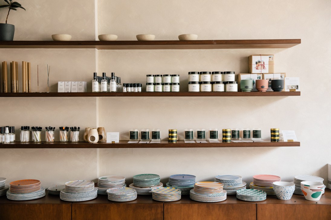 Wooden shelves displaying various products including candles, bottles, and ceramic dishes in organized rows