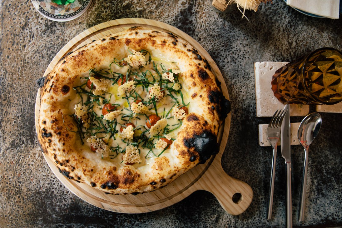 Neapolitan-style pizza with ricotta, cherry tomatoes and herbs on wooden serving board