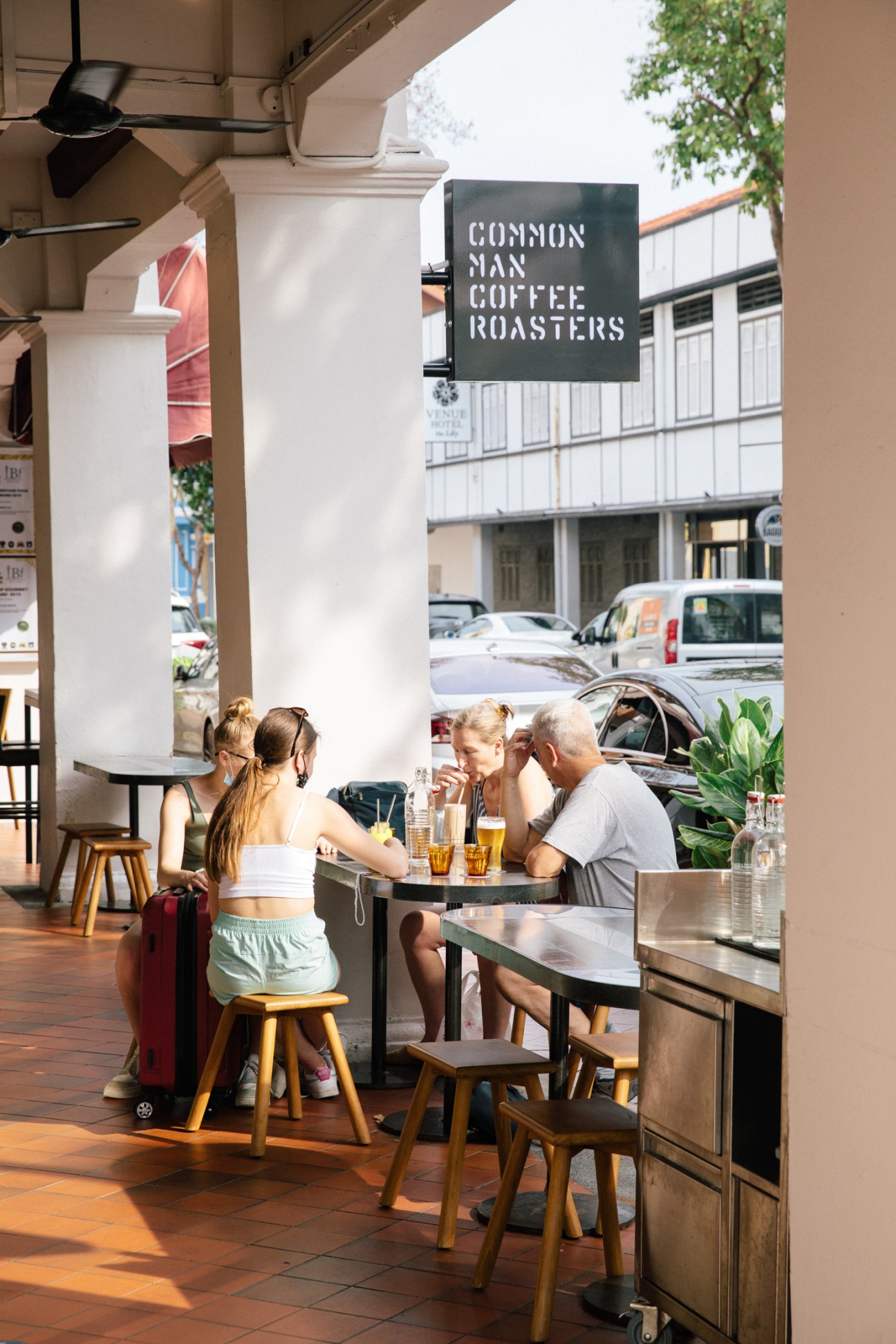 People sitting at outdoor tables drinking coffee at Common Man Coffee Roasters cafe
