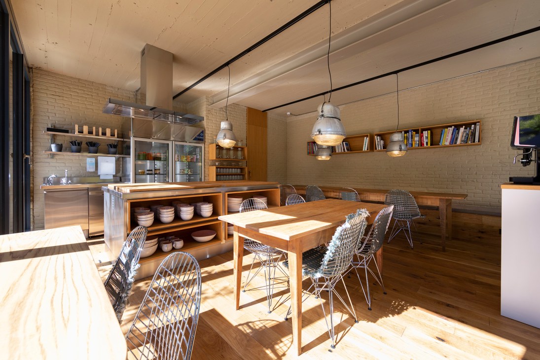 Modern dining space with exposed brick walls, wooden furniture, wire chairs and industrial pendant lighting