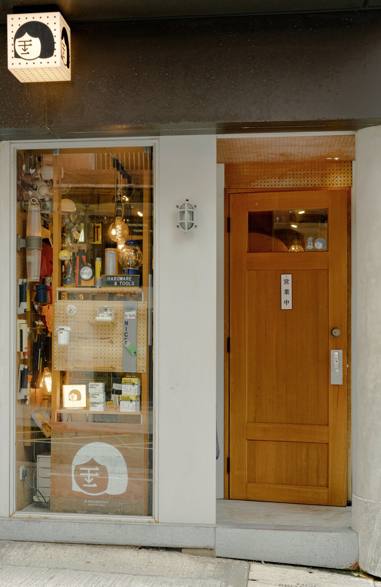 Storefront of Kanamono hardware shop in Hong Kong with wooden door and display window showing tools and hardware items