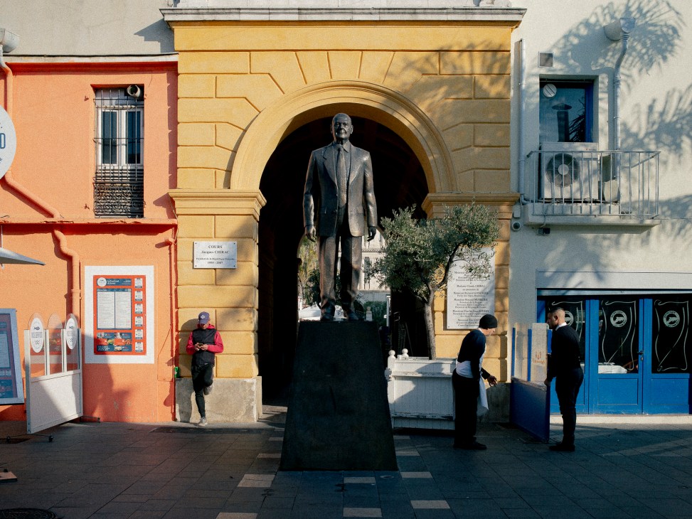 Bronze statue of Jacques Chirac stands in an arched alcove in Nice's old town as people walk by