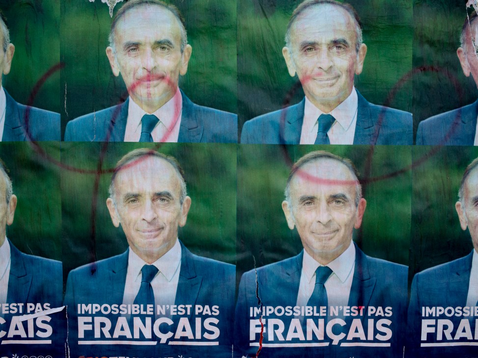 Vandalized French political campaign posters showing a man in suit with red graffiti marks across the faces