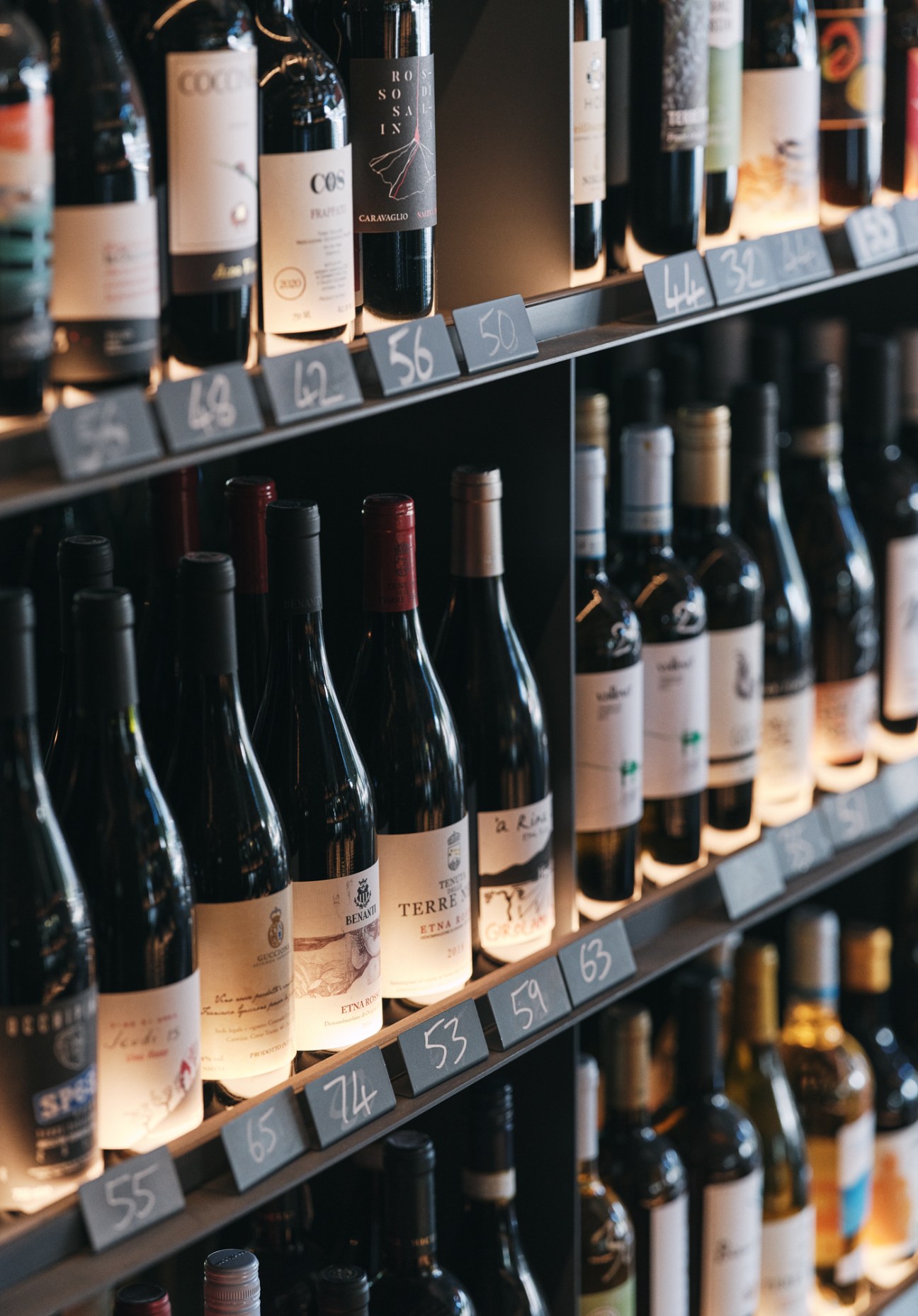 Wine bottles displayed on shelves with numbered price tags in King and Godfree wine cellar