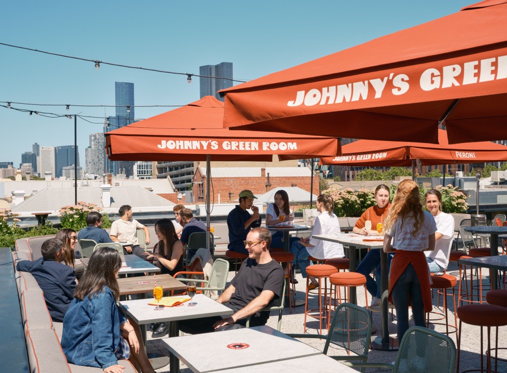 Rooftop terrace dining area with orange umbrellas, tables and chairs, city skyline in background