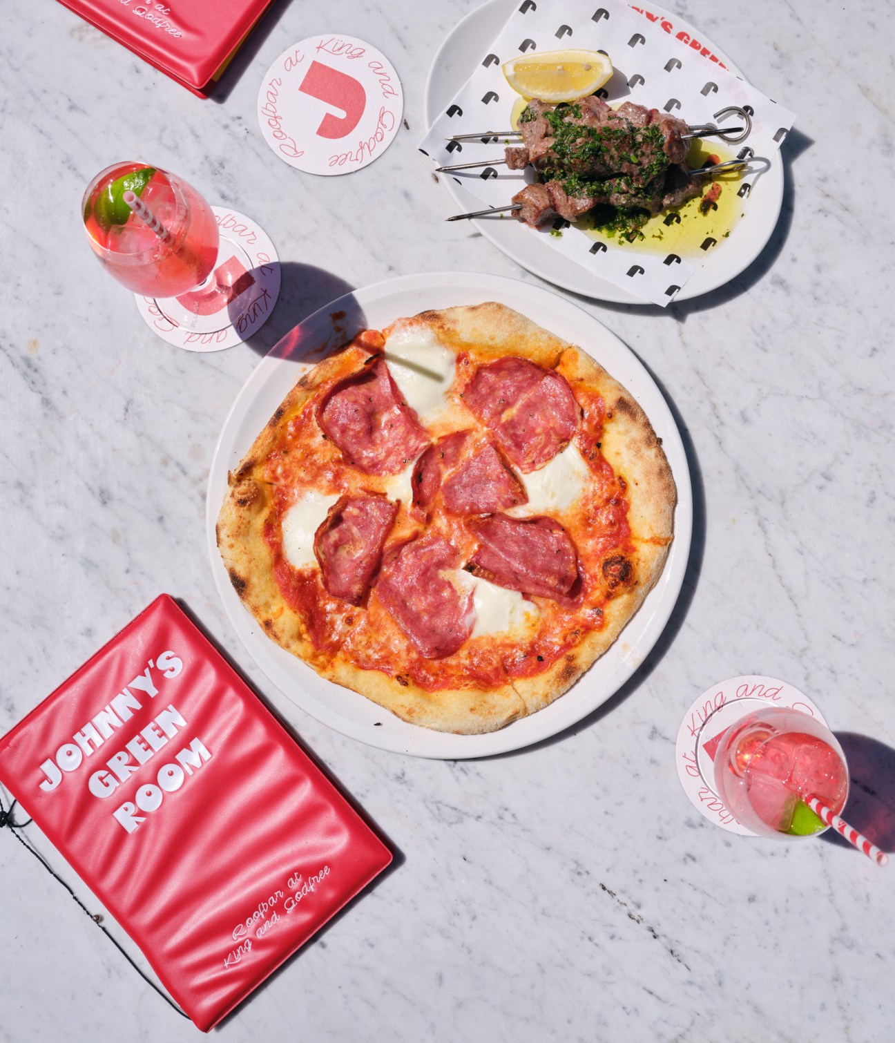 Pizza and cocktails served at Johnny's Green Room rooftop bar with branded glasses and table setting