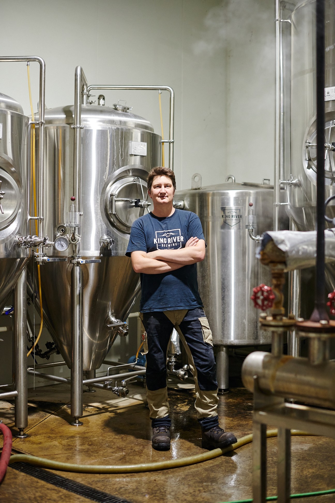 Nathan Munt standing among large stainless steel brewing tanks at King Valley Brewery