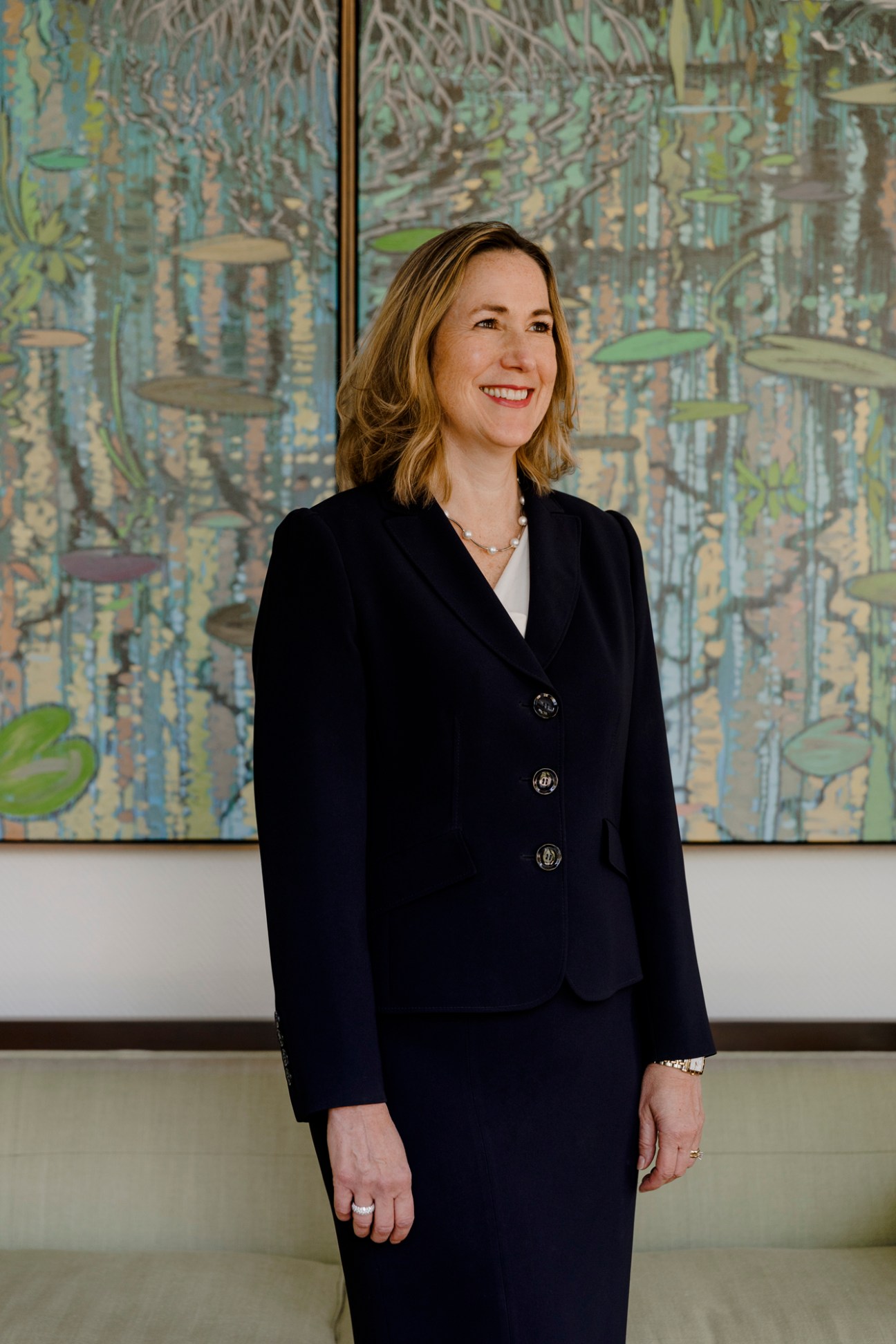 Kirsten Hillman, Canada's ambassador to the US, in a navy blue suit standing in front of colorful artwork