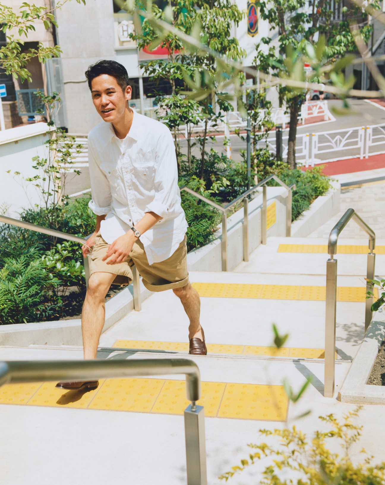 Man in white shirt sitting on bench seating at Kitaya Park surrounded by plants and greenery