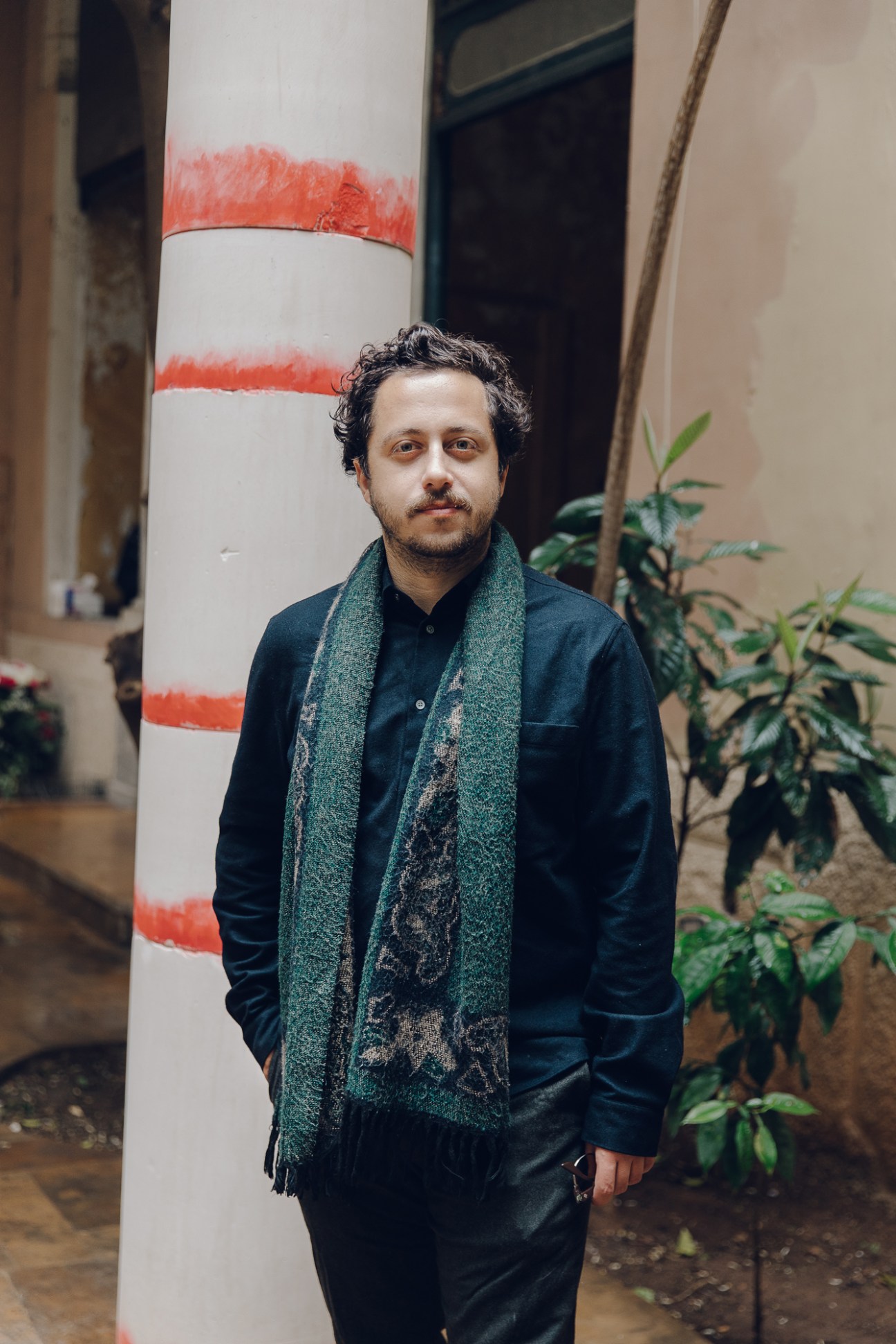 Artist Hussein Nassereddine standing in front of a white column with red stripes