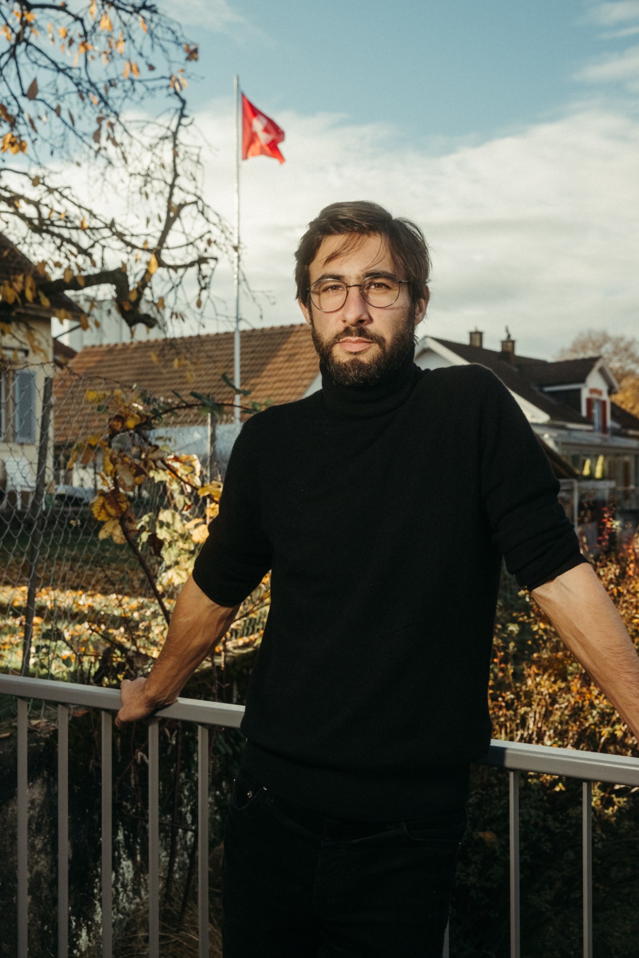 Founder Yves Studer stands on a balcony overlooking Olten with a Swiss flag in the background.