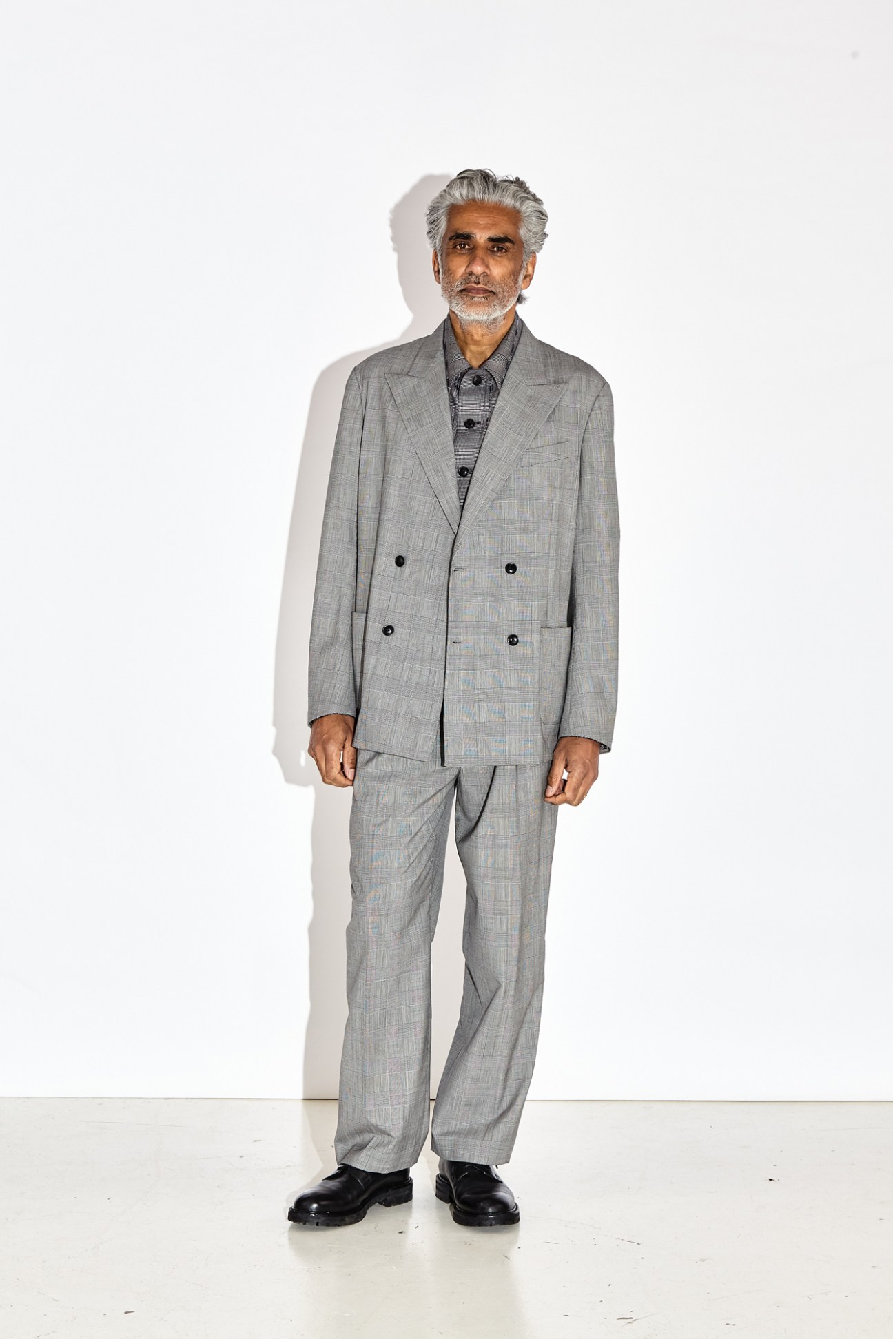 Man in light grey double-breasted suit with relaxed fit standing against white background