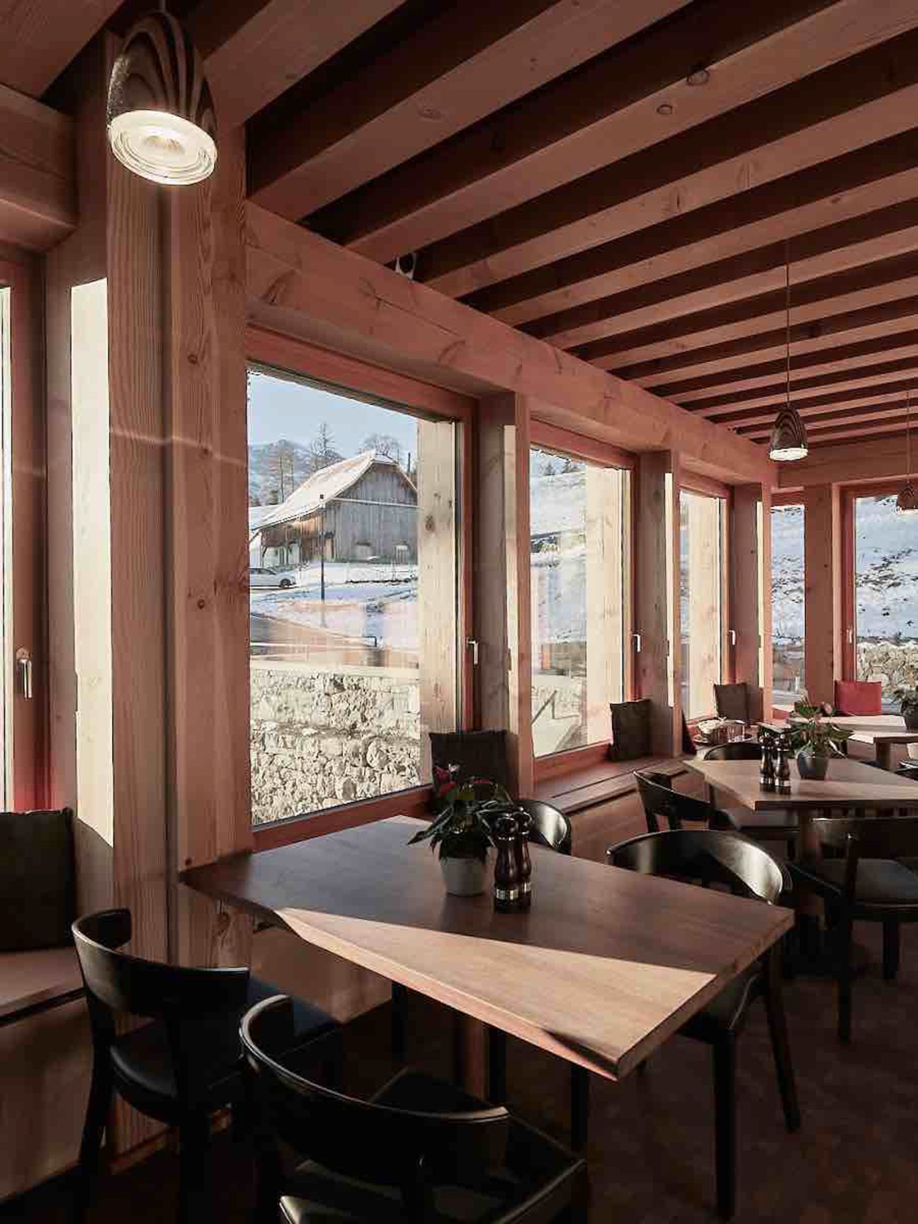Modern restaurant interior with floor-to-ceiling windows overlooking forest at Gasthaus Hergiswald