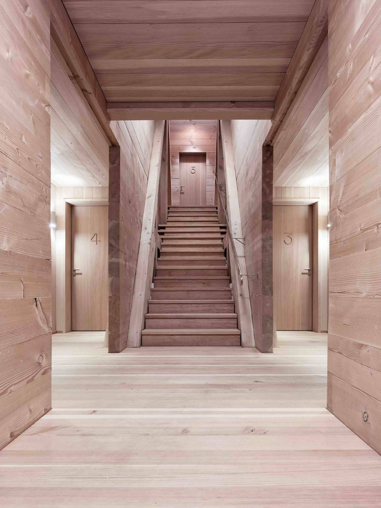 Warm wooden interior hallway with natural timber walls, exposed ceiling beams, and modern lighting fixtures
