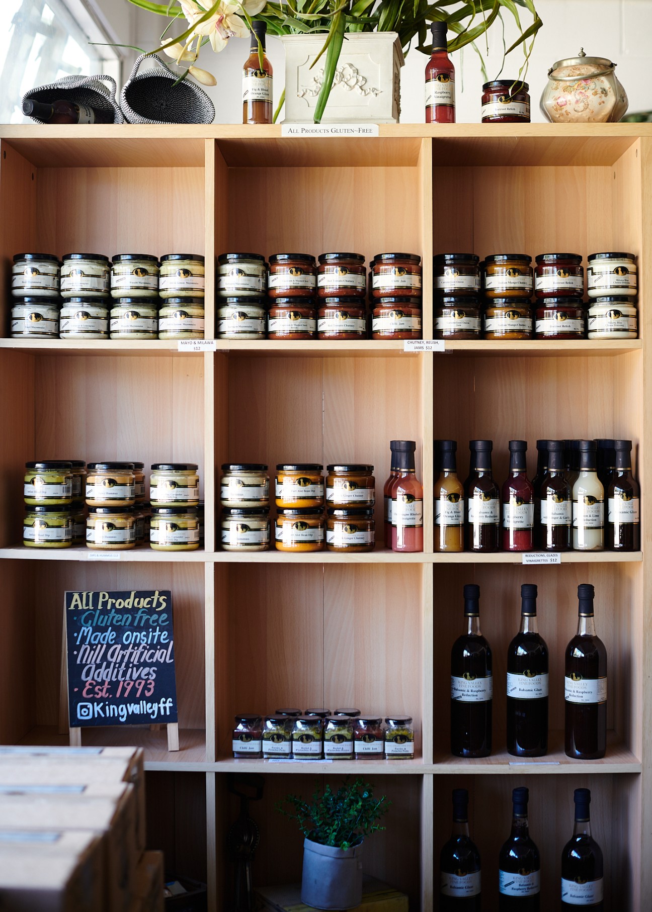 Organized wooden shelves displaying jars of preserves, bottles of wine, and local gourmet products at King Valley Fine Foods