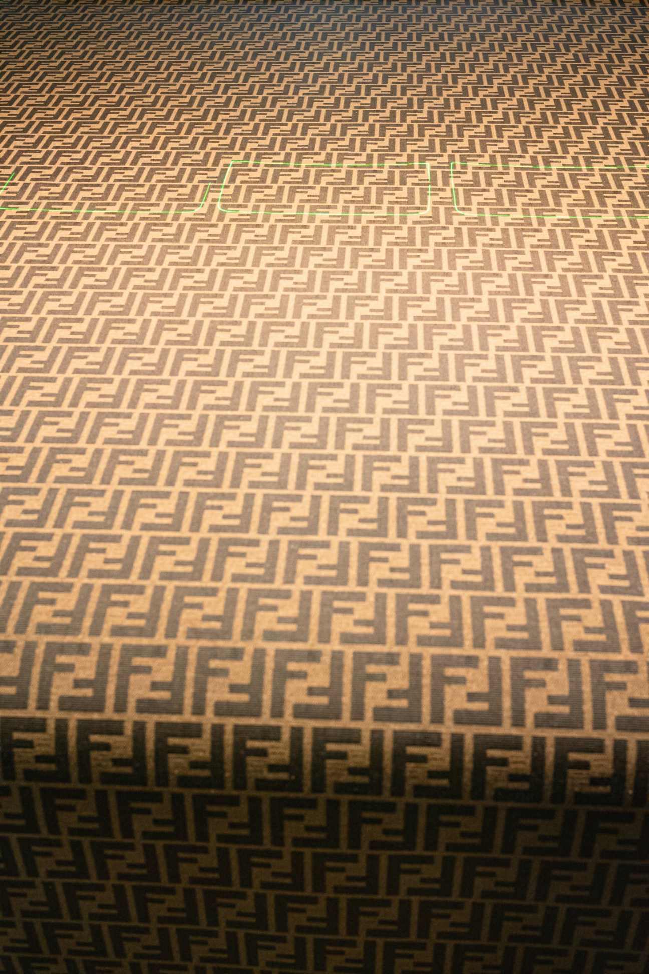 Close-up view of golden-brown fabric with repeating FF logo pattern in geometric grid formation