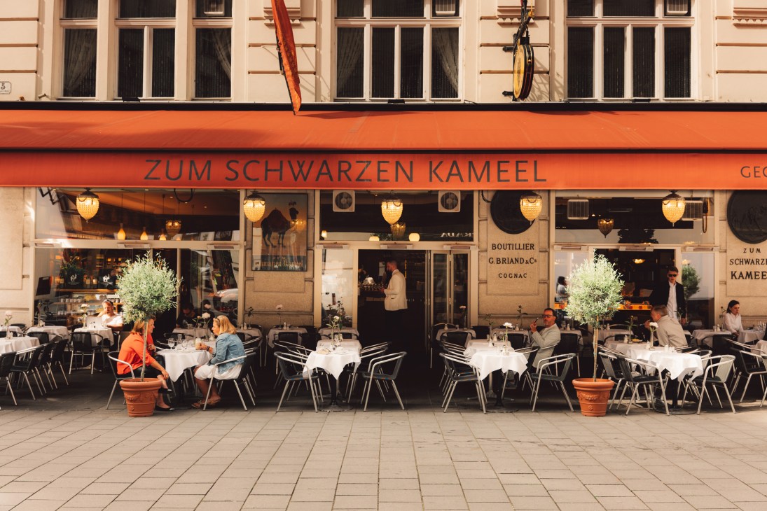 Outdoor cafe terrace with diners at Zum Schwarzen Kameel restaurant in Vienna