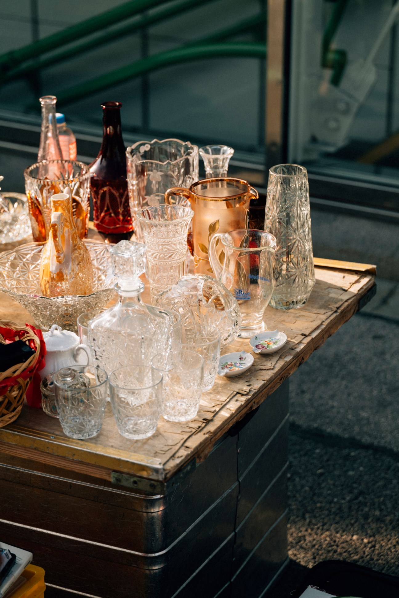 Vintage glassware and bottles displayed on weathered wooden table at flea market