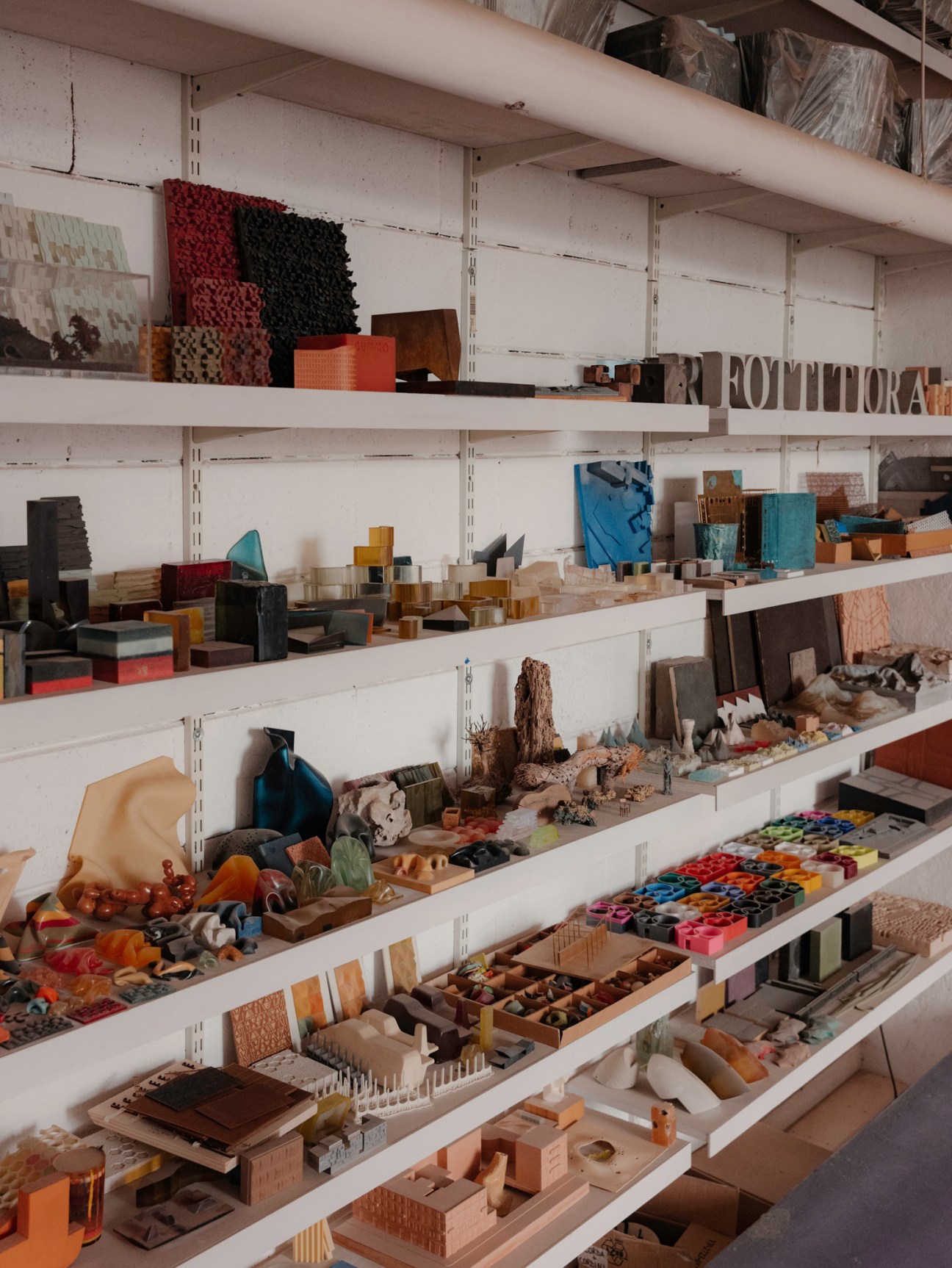 Shelves displaying various architectural model materials, samples and miniature building components in workshop