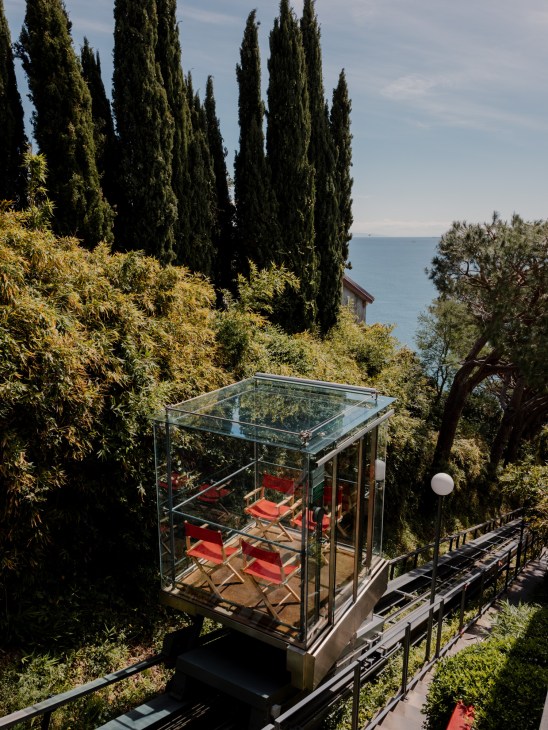 Small funicular railway car on tracks cutting through hillside vegetation leading to Piano's studio