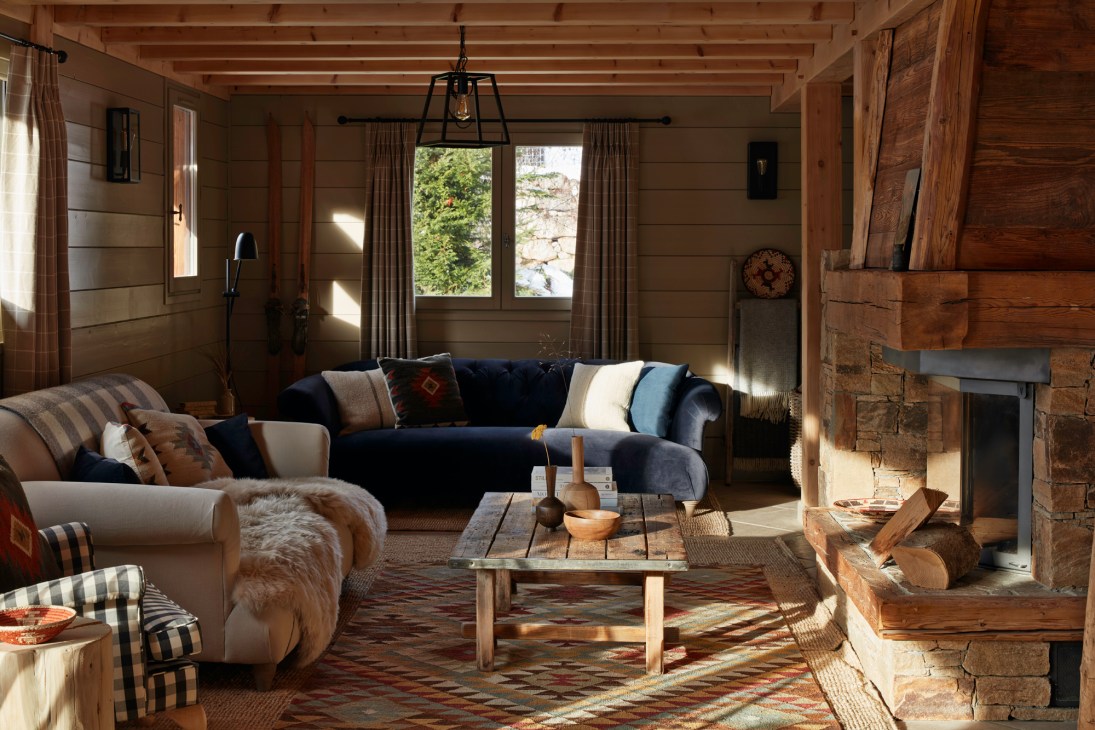 Rustic living room with exposed wooden beams, navy sectional sofa, stone fireplace and neutral color palette