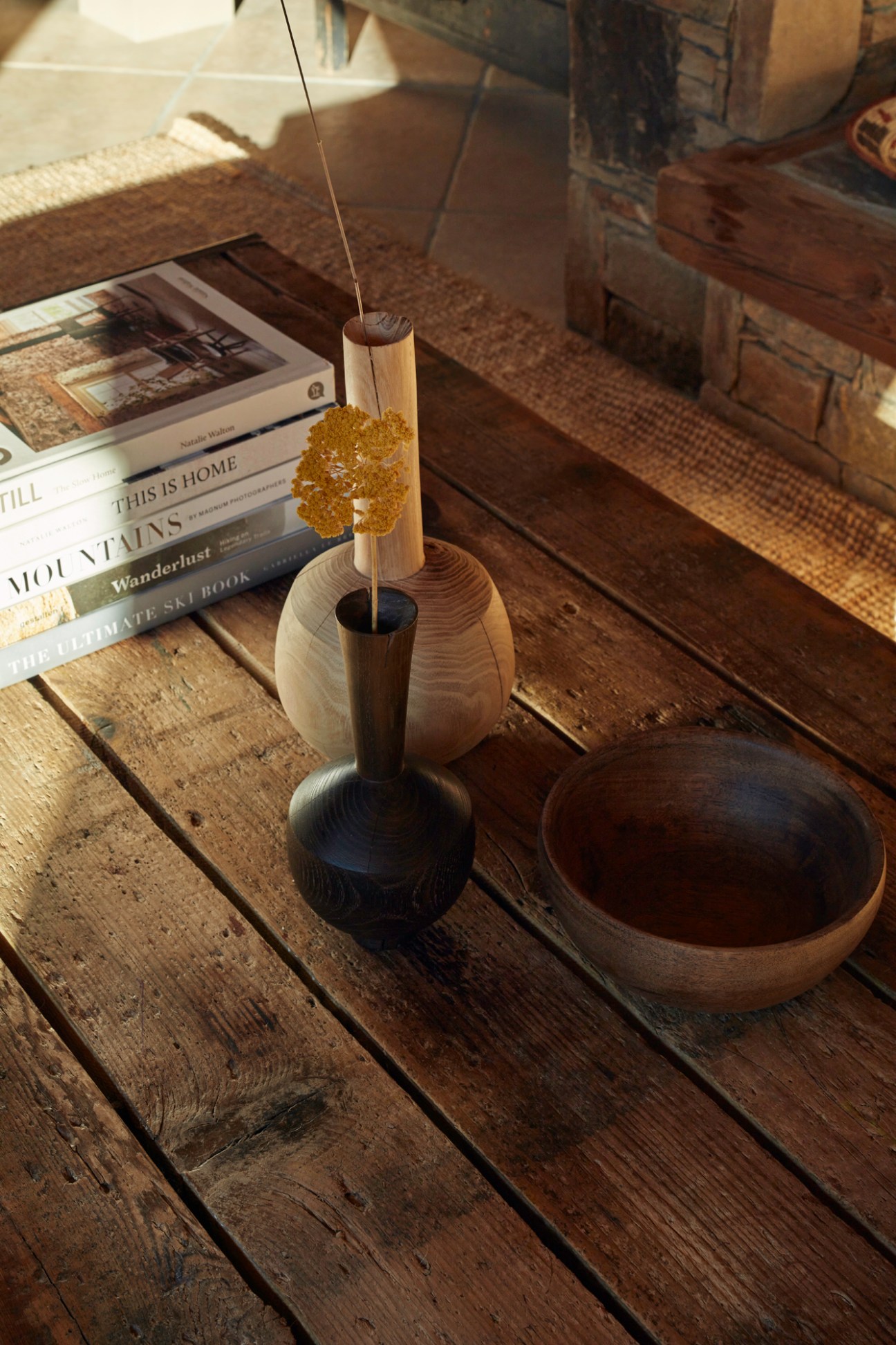Incense stick burning in wooden holder next to ceramic bowl and books on rustic wooden table