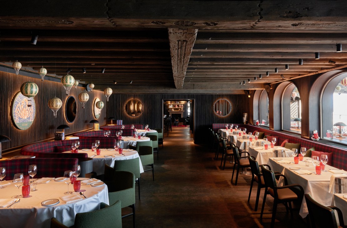 Interior of Langosteria St Moritz restaurant showing open kitchen with glass seafood display and mountain views through windows
