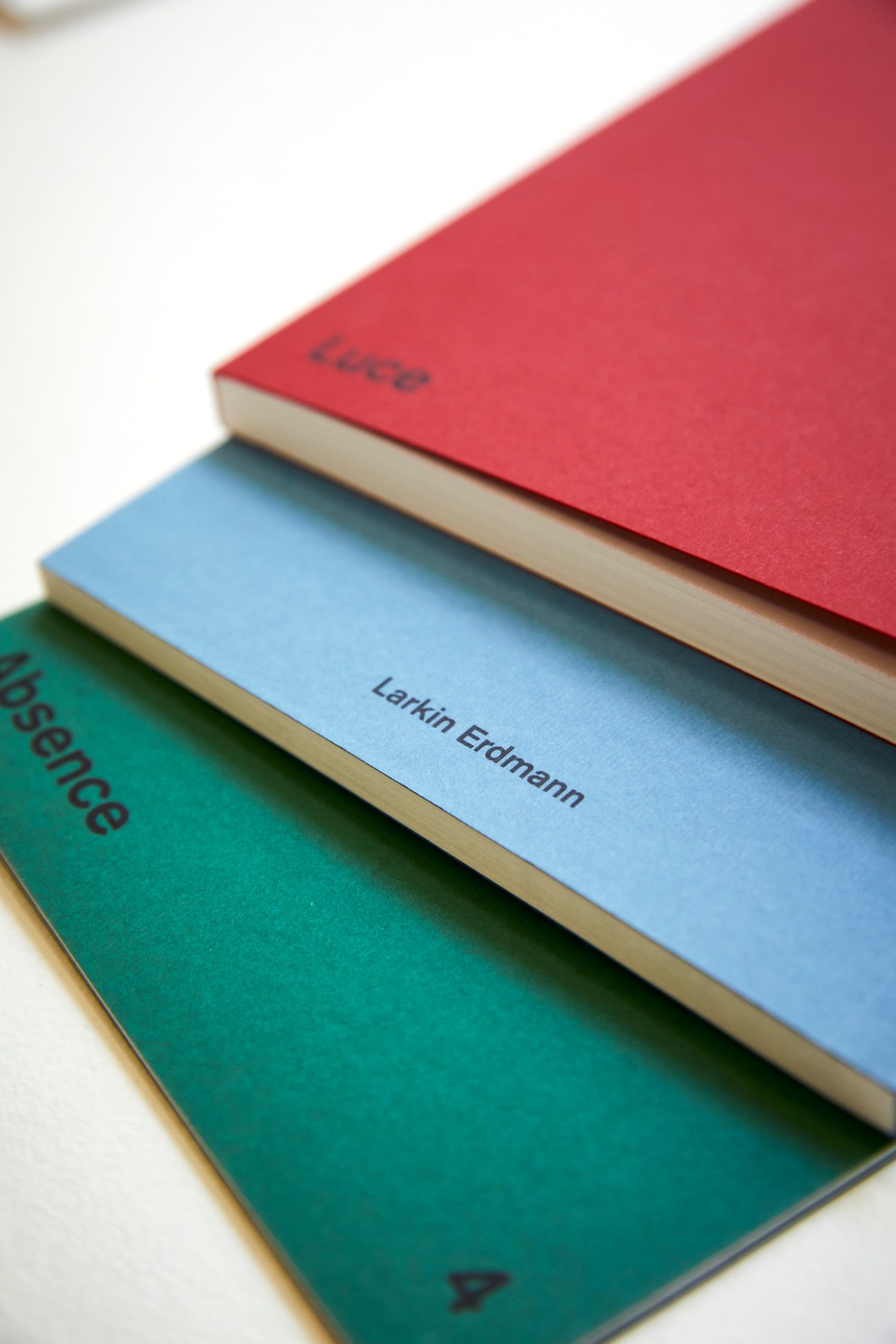 Stack of colorful gallery exhibition brochures and catalogues with Larkin Erdmann name visible