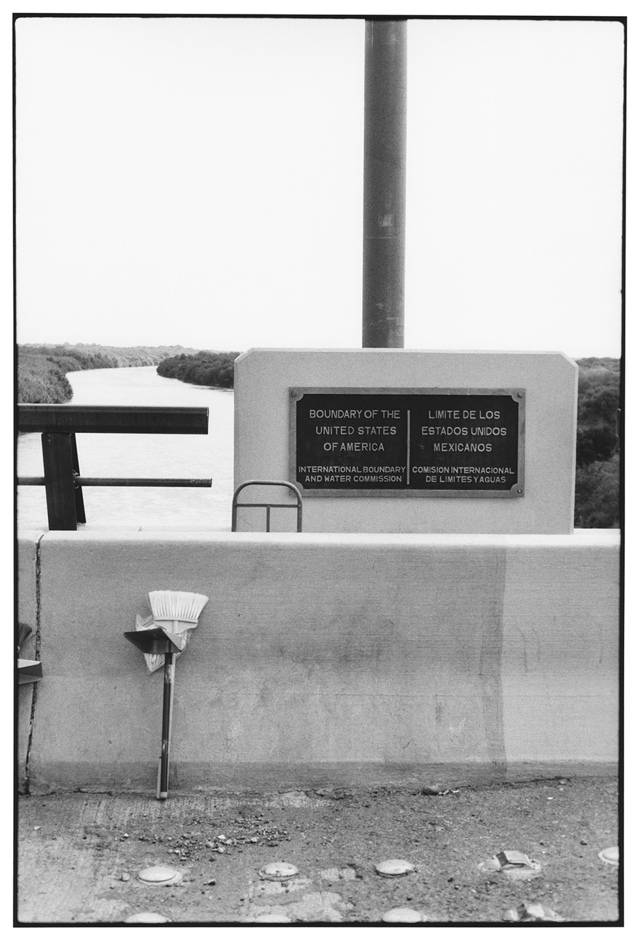 Black and white photograph of US-Mexico border marker and Rio Grande river landscape by Zoe Leonard.