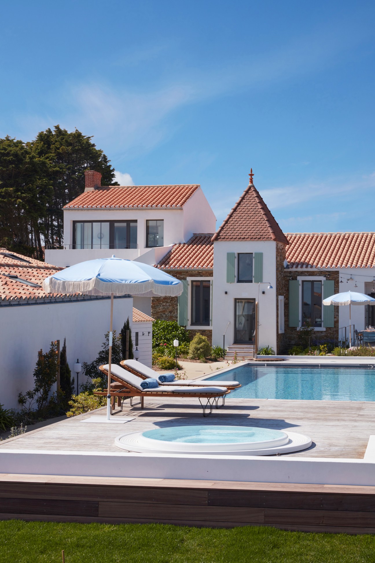 Les Hautes Mers hotel exterior with white Mediterranean-style buildings, terra cotta roofs, pool area and umbrellas