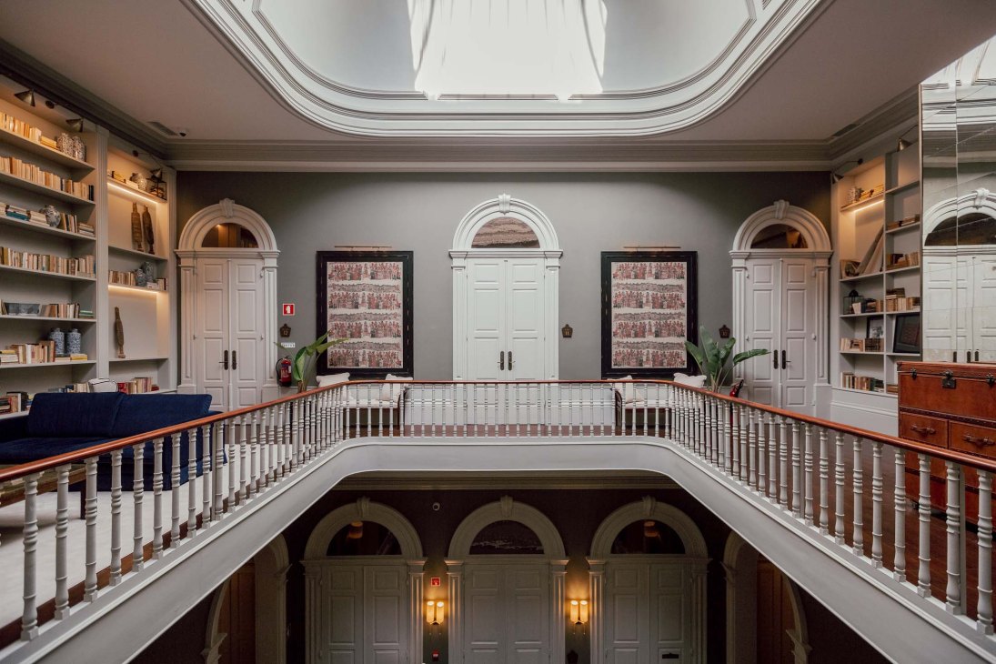Elegant library interior at Torel 1884 with high ceilings, arched doorways, wooden railings and built-in bookshelves.