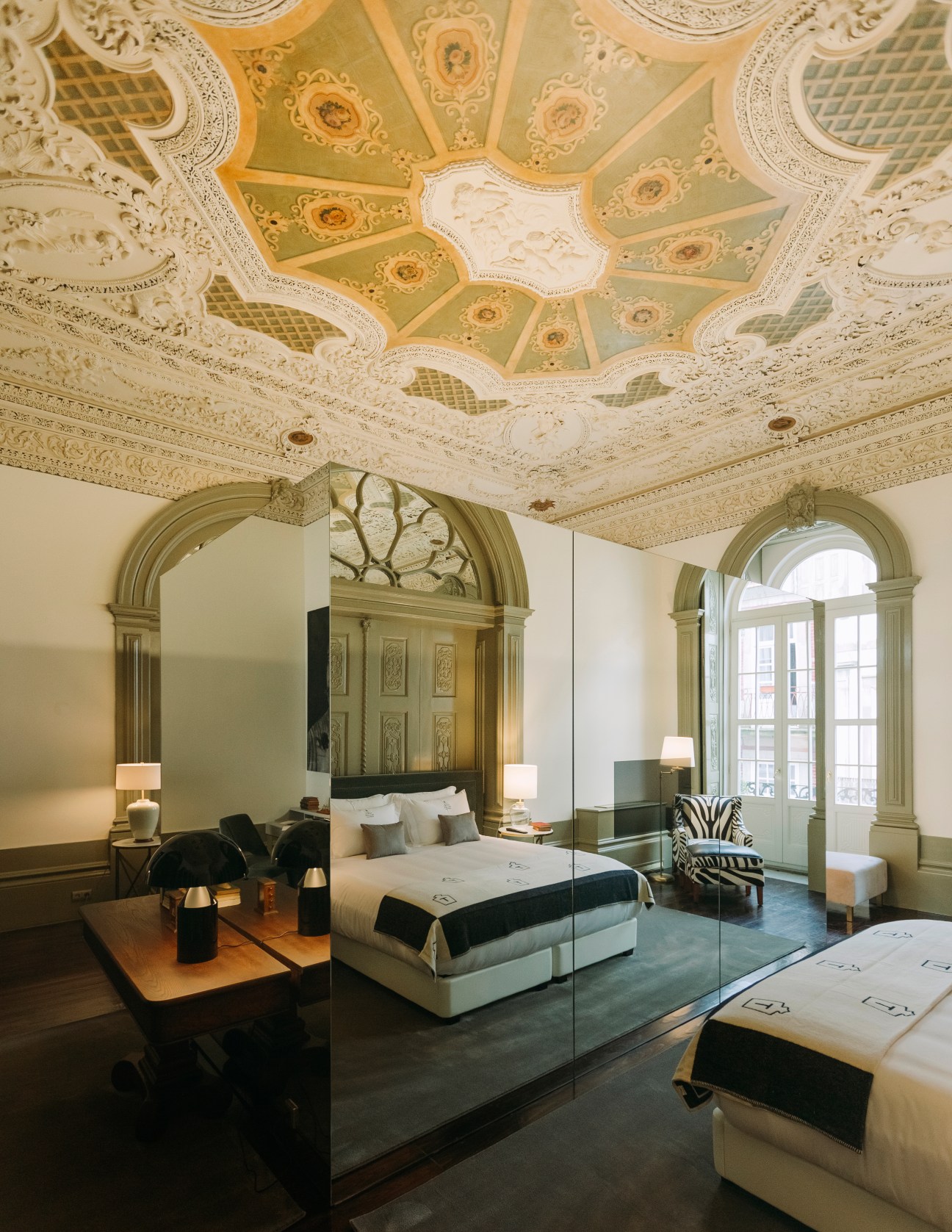 Ornate hotel bedroom ceiling with decorative plasterwork, painted medallions, and geometric patterns at Torel Palace Porto