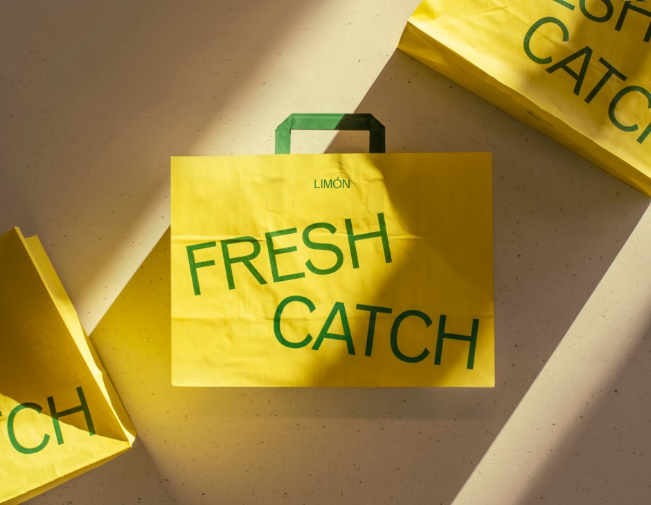 Yellow Limón branded paper bags with green handles displayed against a neutral background.