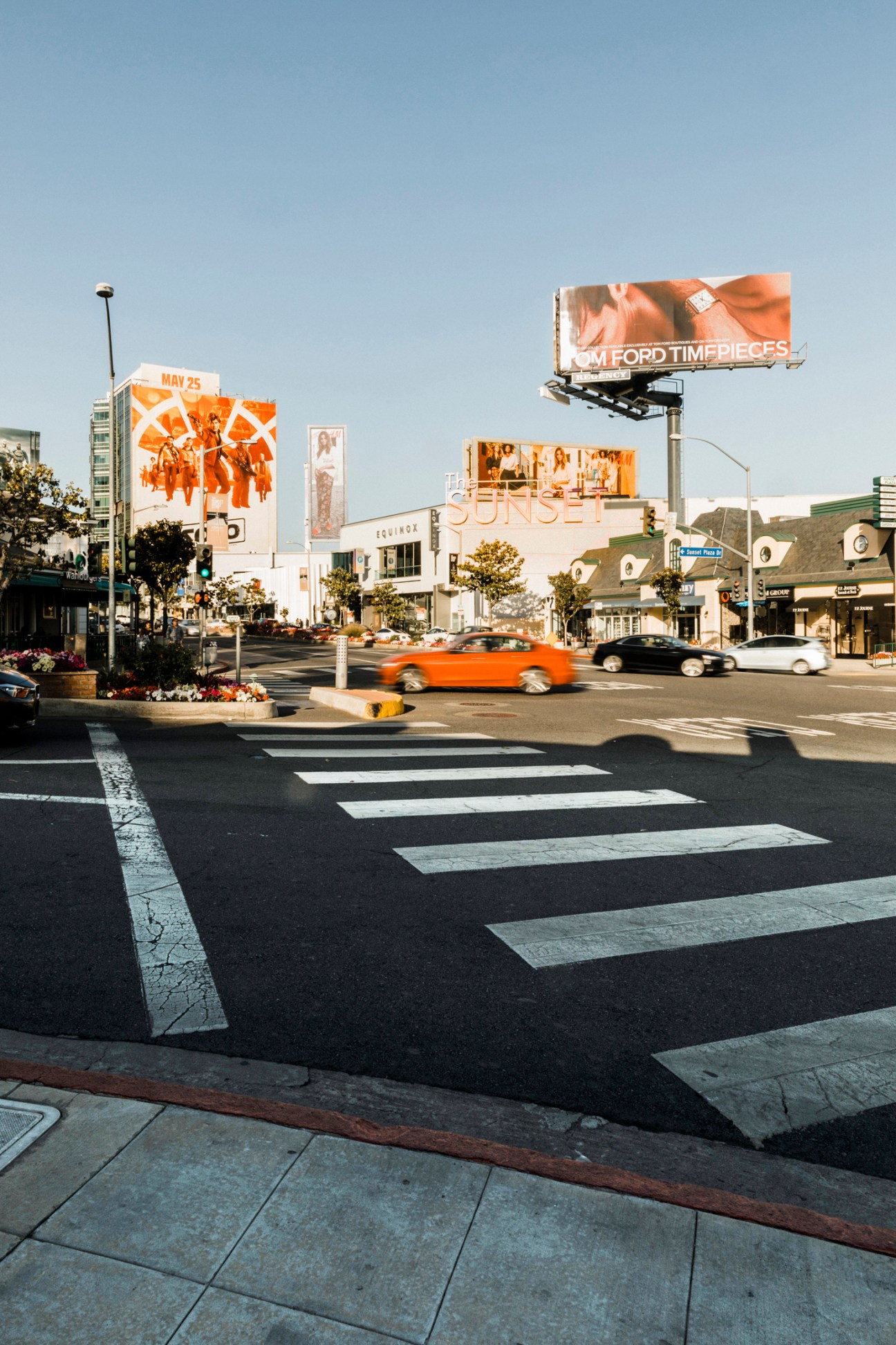 Street scene on Sunset Boulevard in Los Angeles with billboards, cars, and crosswalk