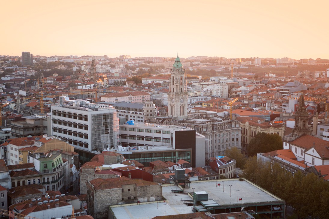 Aerial view of Porto cityscape with historic church spire and terracotta roofed buildings at sunset
