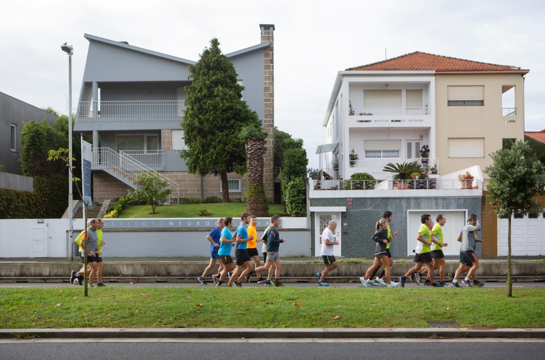 Runners exercising along a waterfront path past modern residential buildings in Porto.