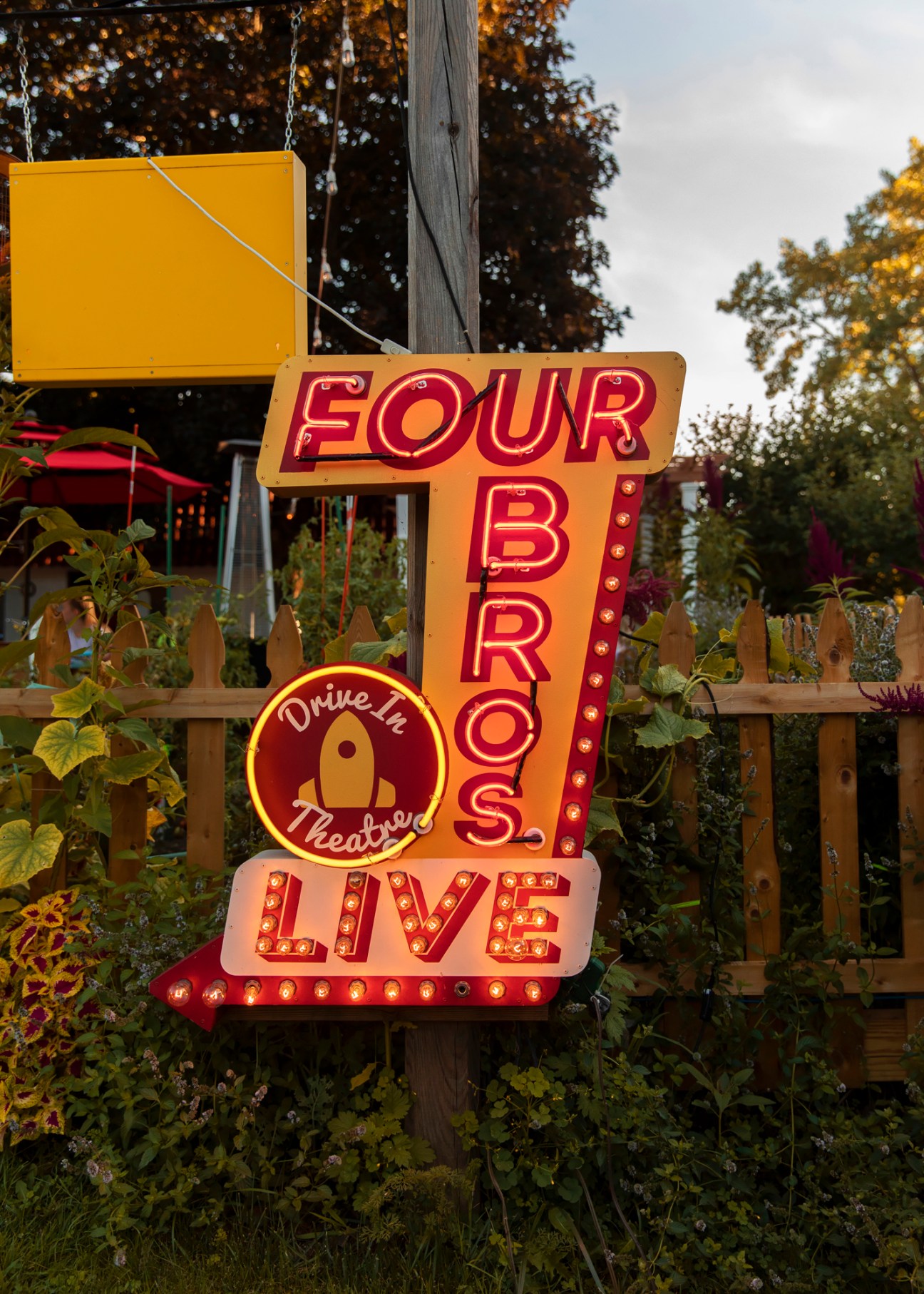 Illuminated vintage-style sign reading 'FOUR BROS LIVE' with 'Drive In Theatre' in a circular logo