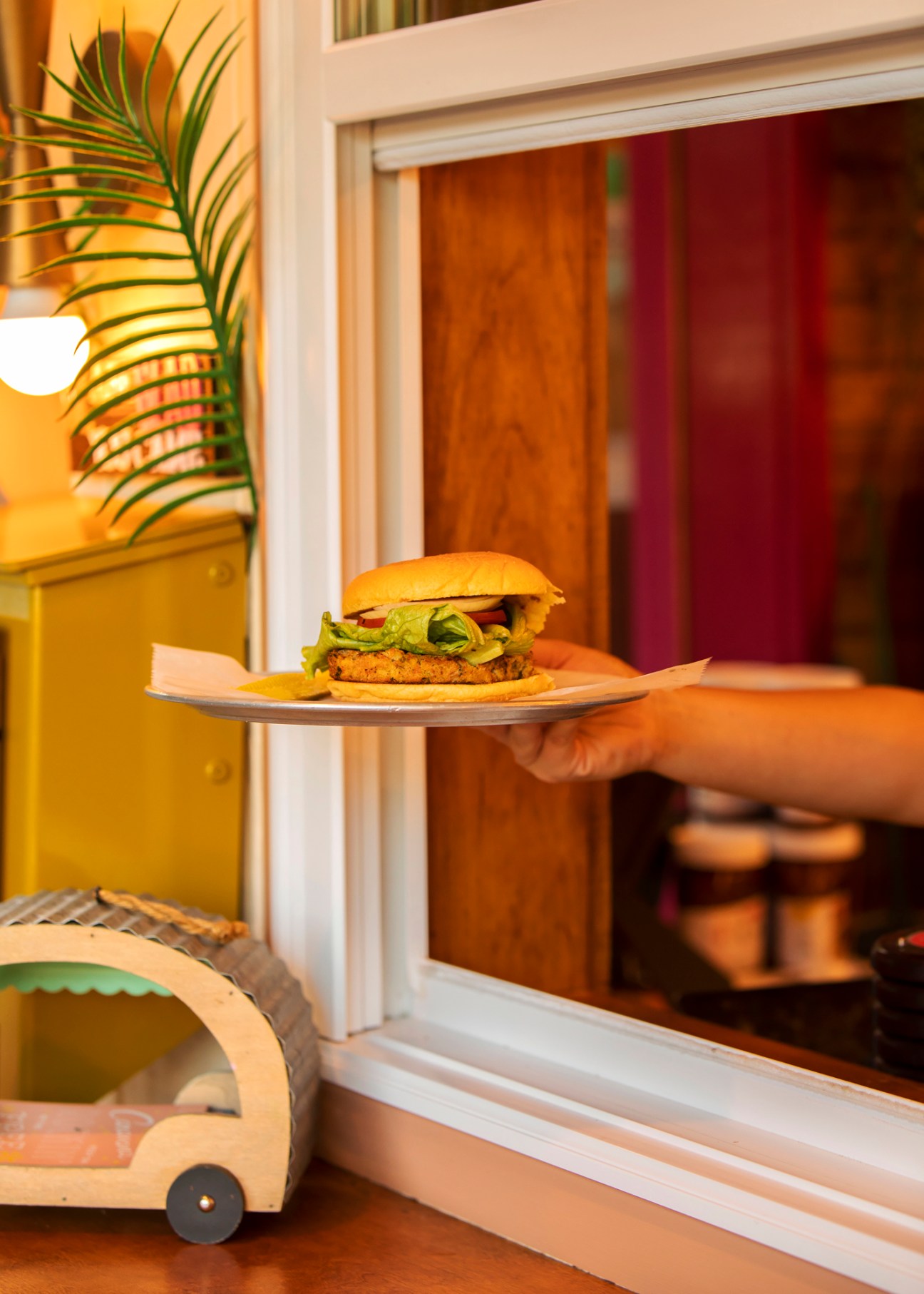 Hand holding a plate with a burger on it at Four Brothers drive-in cinema