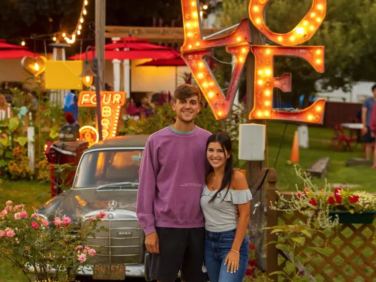 man and woman in front of car and love sign
