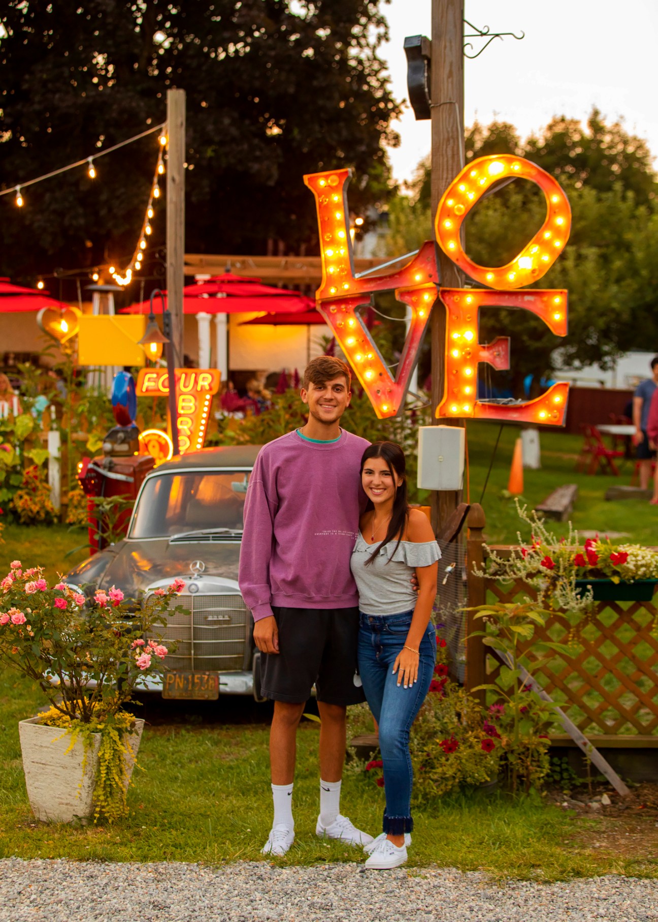 Young couple posing in front of illuminated LOVE sign at Four Brothers drive-in cinema