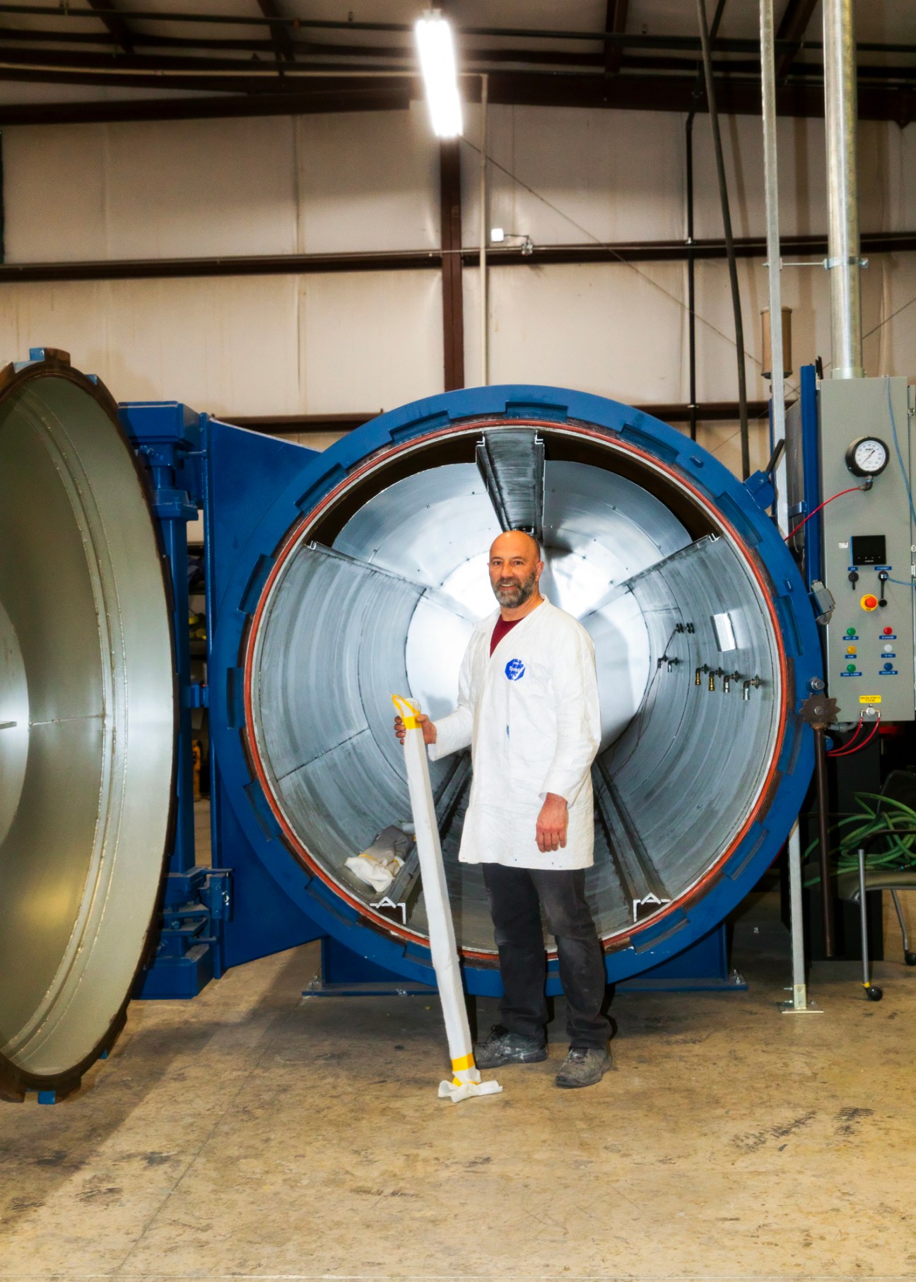 Jim DeSousa standing in front of a large cylindrical industrial chamber at Composite Energy Technologies