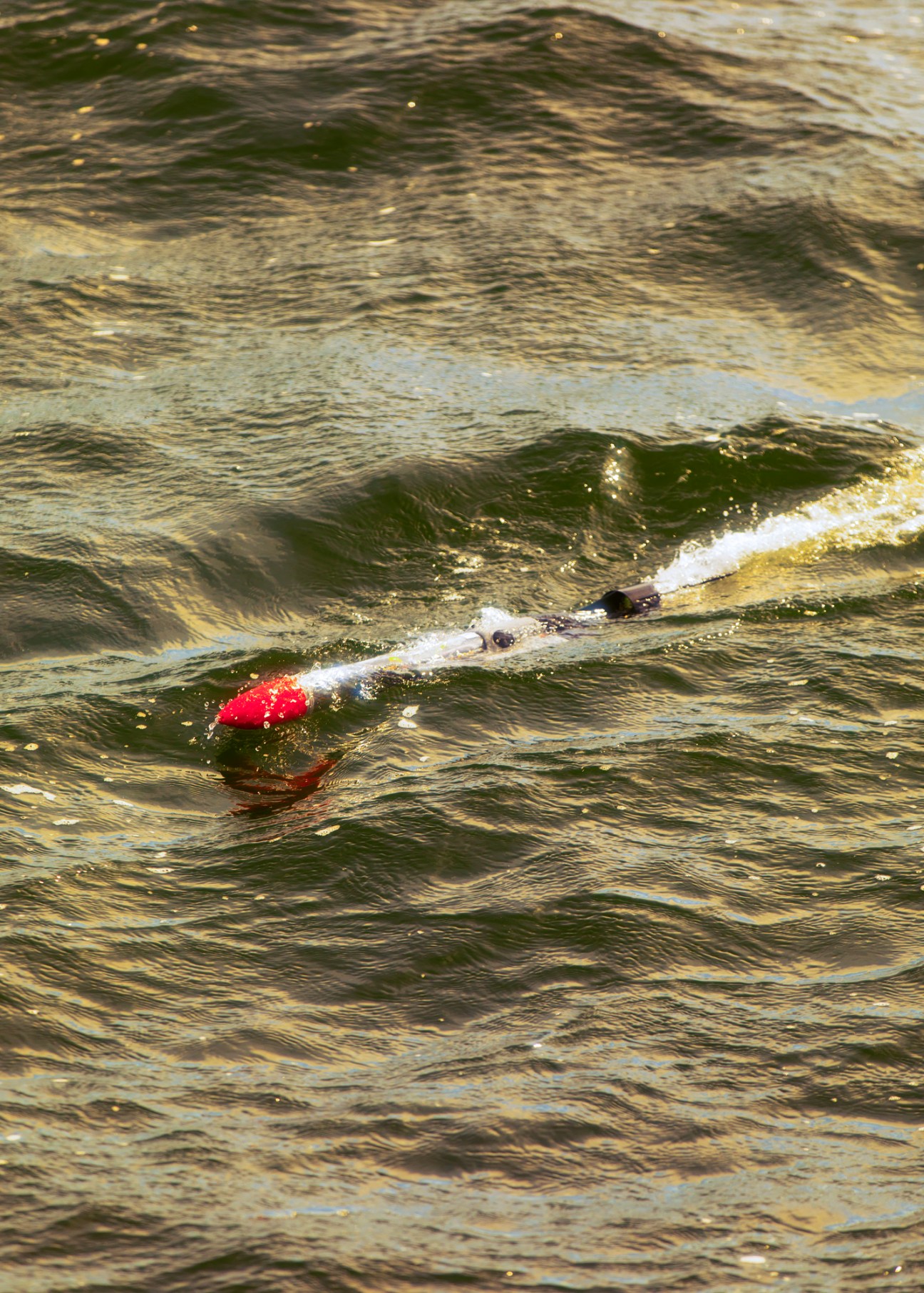 Red and white Jaiabot autonomous vehicle floating in choppy water