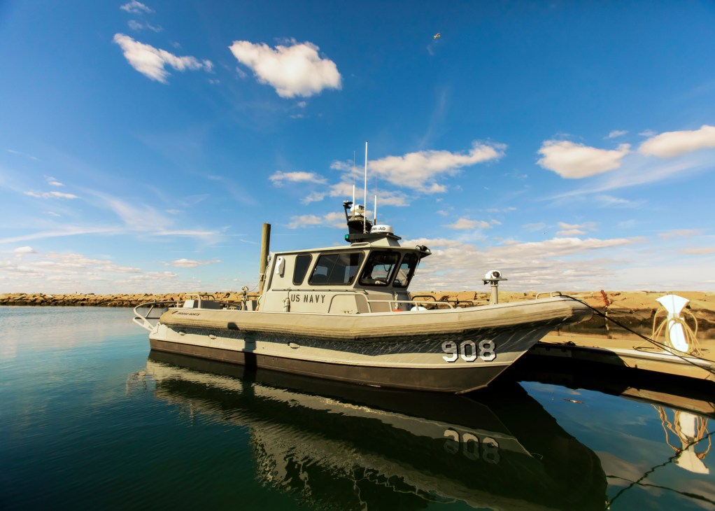 US Navy patrol boat numbered 908 docked at harbor with communications equipment on top