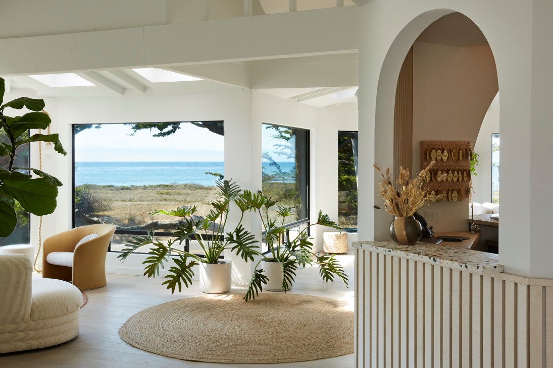 White Water hotel lobby with coastal views, featuring curved seating, plants, and ocean vista through large windows.